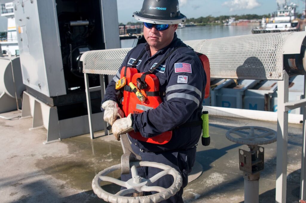 A trainer in uniform providing a demonstration to a trainee who is in the second half of the AccuTRANS tankerman school.